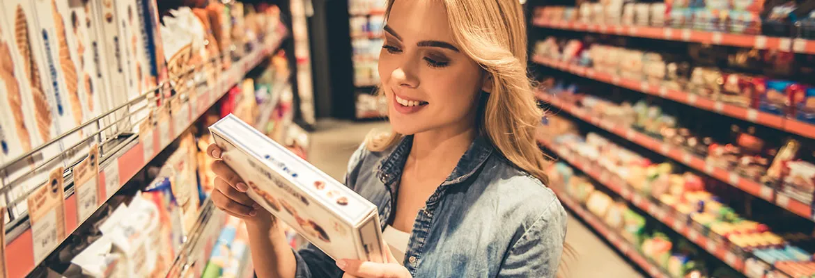 Frau welche im Supermarkt Rückseite einer Lebensmittelverpackung durchliest Frau welche im Supermarkt Rückseite einer Lebensmittelverpackung durchliest