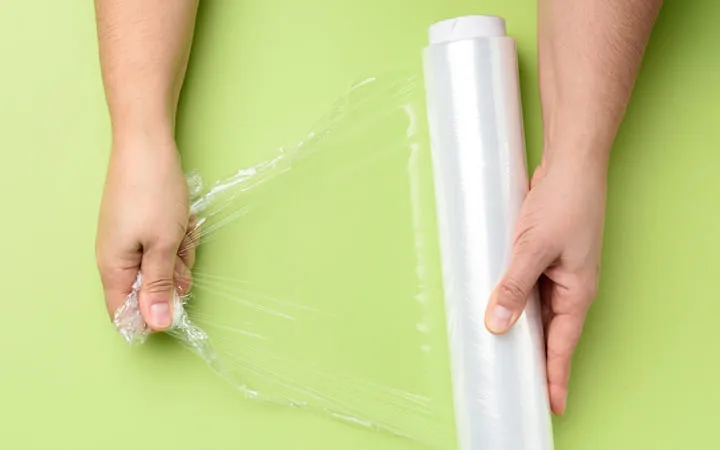 Person zieht Polyethylenfolie von einer Rolle Person zieht Polyethylenfolie von einer Rolle