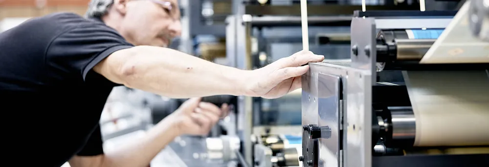 Uomo in piedi davanti a una macchina per la stampa di etichette Uomo in piedi davanti a una macchina per la stampa di etichette