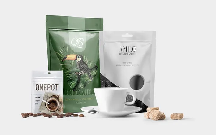 Drei Beutelverpackungen in unterschiedlichen Größen für Kaffeebohnen mit einer Kaffee Tasse Drei Beutelverpackungen in unterschiedlichen Größen für Kaffeebohnen mit einer Kaffee Tasse